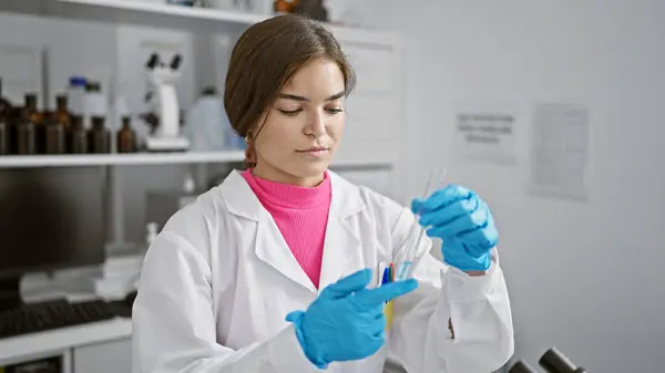 Portrait of a dedicated young hispanic woman, a beautiful scientist, diligently measuring liquid in a lab as part of her biology research work, embodying the graceful blend of beauty and science.