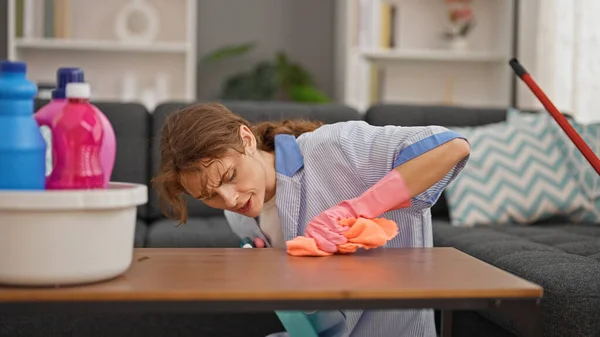 Young woman professional cleaner cleaning table make an effort at home