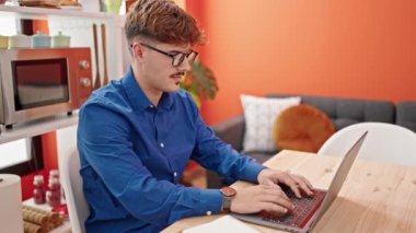 Evde dizüstü bilgisayarda çalışan genç adam.