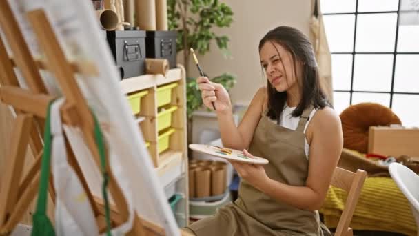 美しく 焦点を当てた若いヒスパニック系女性アーティストが椅子に座り 創造性に浸り アートスタジオで屋内で絵を描く — ストック動画