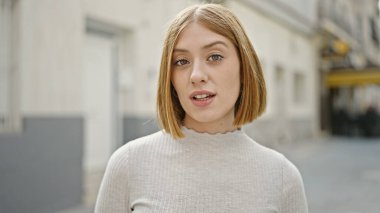 Sokakta kendine güvenen genç sarışın kadın gülümsüyor