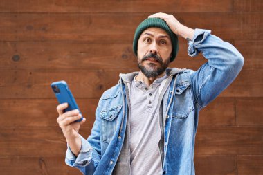 Akıllı telefon kullanan genç bir İspanyol, kafası karışık, şaşırmış ve sinirli bir yüz ifadesi takınıyor. 