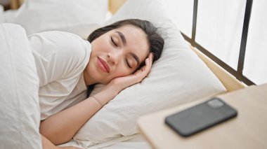 Genç, güzel, İspanyol bir kadın yatakta uzanıyor.