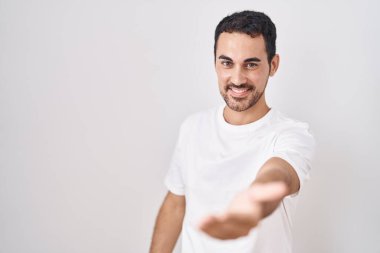 Beyaz arka planda duran yakışıklı İspanyol adam gülümsüyor. Avuç içi dolusu yardım eli uzatıyor ve kabul ediyor.. 