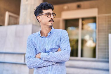 Young caucasian man standing with arms crossed gesture and relaxed expression at street