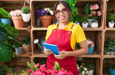 Young beautiful arab woman florist smiling confident using touchpad at flower shop