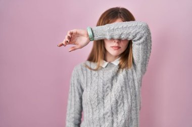 Pembe arka planda duran güzel bir kadın kollarıyla gözlerini kapatıyor, ciddi ve üzgün görünüyor. Görme, saklama ve reddetme konsepti 