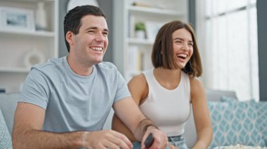 Evdeki kanepede oturup televizyon izleyen güzel bir çift.