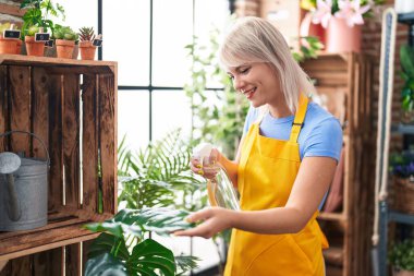 Çiçekçide çalışan sarışın bir çiçekçi.