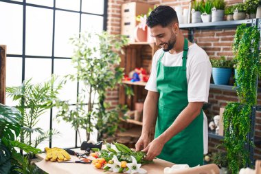Genç Arap çiçekçi çiçekçi çiçekçide buket çiçek yapar.