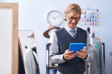 Elbise fabrikasında dokunmatik ped kullanan kendine güvenen genç sarışın bir terzi.