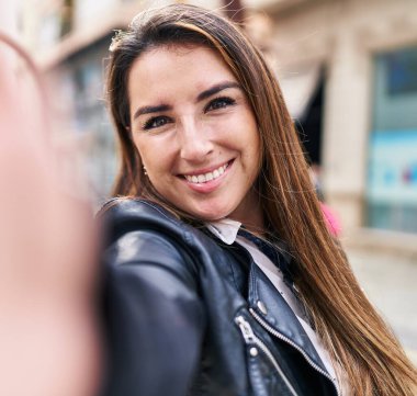 Genç ve güzel İspanyol kadın gülümsüyor. Kendine güvenen. Sokakta kamerayla selfie çekiyor.