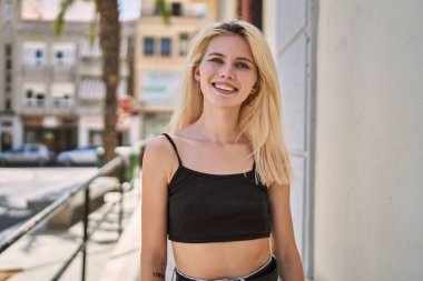 Sokakta kendine güvenen genç sarışın kadın gülümsüyor