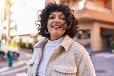 Young beautiful hispanic woman smiling confident looking to the side at street