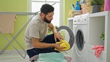 Çamaşırhanede çamaşır yıkayan İspanyol genç adam.