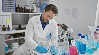 Genç İspanyol bilim adamı laboratuarda oturmuş rapor yazıyor.