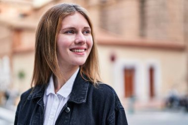 Young blonde woman smiling confident looking to the side at street