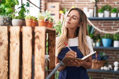 Çiçekçide kendine güvenen genç sarışın bir çiçekçi.