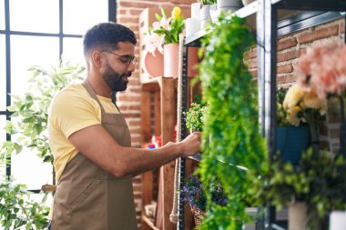 Çiçekçide duran çiçekçi genç Arap adam.