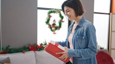 Kafkasyalı genç bir kadın elinde Noel hediyesiyle evde dikiliyor.