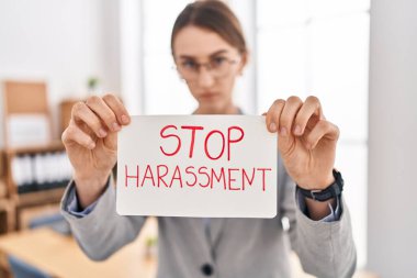 Kafkasyalı genç bir iş kadını, elinde tacize son verme pankartı tutuyor.