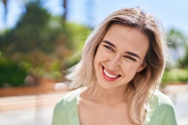 Gülümseyen genç bir kadın sokağın kenarına bakıyor kendinden emin.