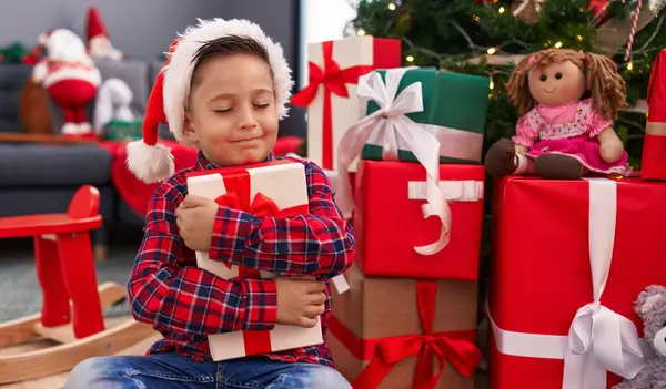 Adorable Hispanic Boy Hugging Christmas Gift Sitting Floor Home — Stock Photo, Image