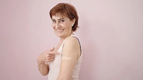 Mature Hispanic Woman Pointing Band Aid Arm Isolated Pink Background — Stock Photo, Image