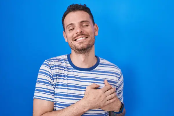 Young Hispanic Man Standing Blue Background Smiling Hands Chest Closed — Stock Photo, Image
