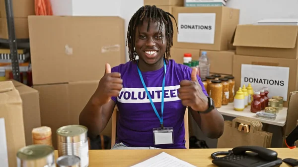 African american man volunteer smiling confident doing thumbs up gesture at charity center