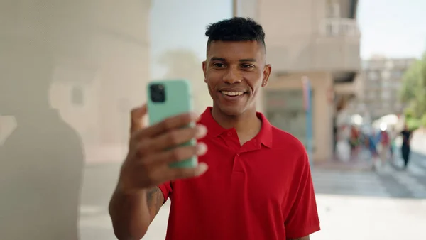Young latin man smiling confident having video call at street