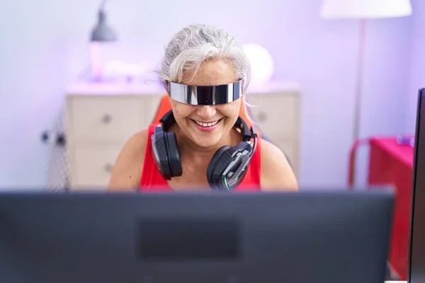 中世の白髪の女性のストリーマーは ゲームルームで仮想現実のメガネを使用してビデオゲームをプレイ — ストック写真