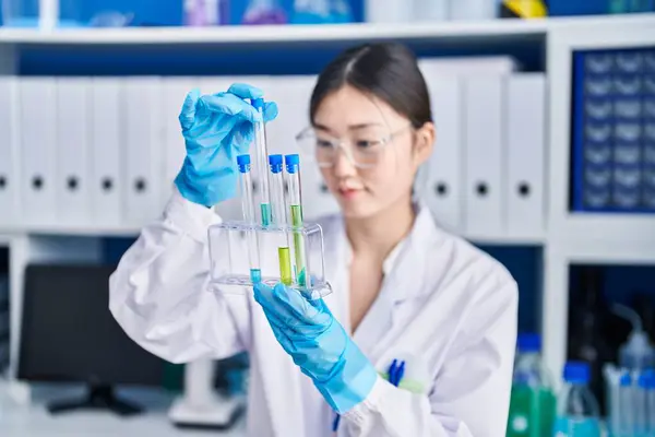 Chinese woman scientist holding test tubes at laboratory