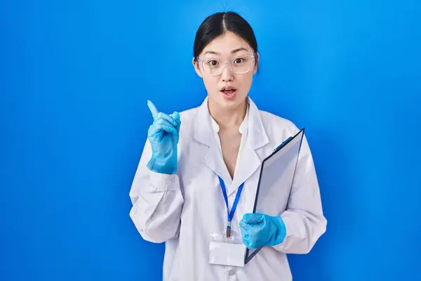 在科学家实验室工作的中国年轻女子惊讶地指指点点旁边 张开嘴惊讶的表情 — 图库照片