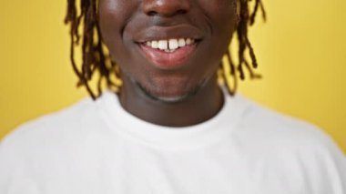 Afro-Amerikalı adam, izole edilmiş sarı arka planda gülümsüyor.