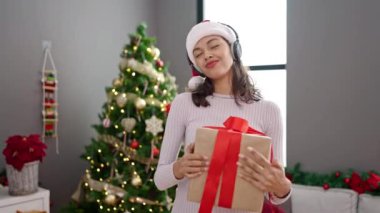 Ev içinde, oturma odasında hediyeli ve noel ağacı olan bir kadın.