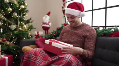 Mutlu adam Noel 'i evde kutluyor, Noel hediyesini açıyor.