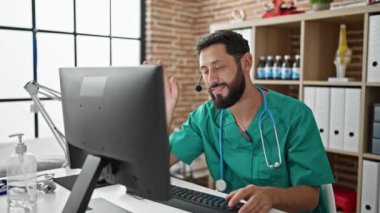 Genç İspanyol doktor, klinikte bilgisayarla video görüşmesi yapıyor kulaklığı çıkartıyor.