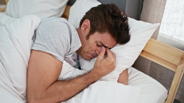 寝室で泣いている悲しい表情でベッドに横たわる若いヒスパニックの男 — ストック動画