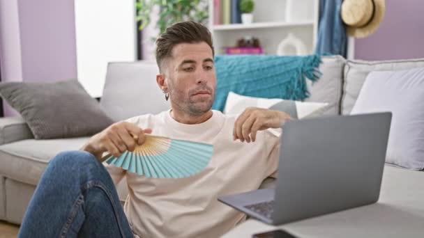 麻烦大了 专心致志的惊慌失措的男人坐在客厅地板上 在家里用手扇 在笔记本电脑上上网工作时汗流浃背 — 图库视频影像