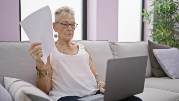 Skupiona Siwowłosa Starsza Kobieta Głęboko Skoncentrowana Korzystająca Laptopa Trzymająca Dokumenty — Wideo stockowe