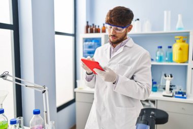 Genç Arap bilim adamı laboratuarda çalışan dokunmatik ped kullanıyor.