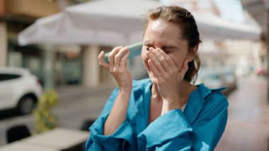 Caddedeki akıllı telefondan kendine güveni tam bir sesli mesaj dinleyen genç bir kadın.