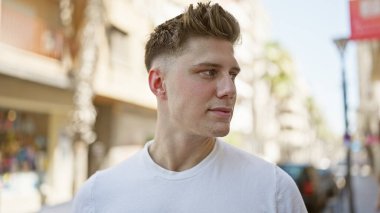 Genç, yakışıklı, beyaz, sakin ama ciddi bir yüz ifadesi sergiliyor, açık havada güneşli bir havada dikilirken yan tarafa bakıyor. Sokak modası şehir ve havalı yaşam tarzını gözler önüne seriyor.