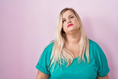 Pembe arka planda duran beyaz tenli kadın uykulu ve yorgun görünüyor, yorgunluk ve akşamdan kalmalıktan yorgun, sabahları tembel gözler.. 