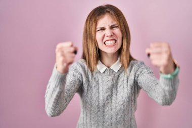 Güzel bir kadın, öfkeyle bağırırken kızgın ve kızgın bir şekilde yumruklarını kaldırıyor. öfke ve agresif konsept. 