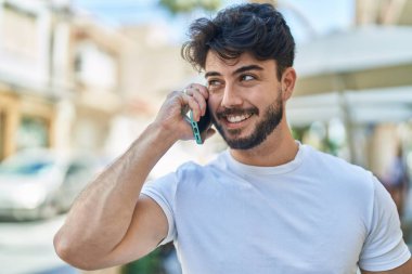 Genç İspanyol adam gülümsüyor. Kendine güveniyor. Sokakta akıllı telefondan konuşuyor.