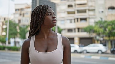 Sokakta ciddi bir ifadeyle gökyüzüne bakan Afrikalı Amerikalı kadın.