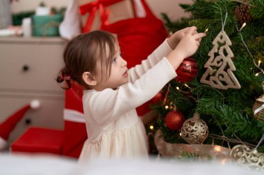 Noel ağacını süsleyen sevimli kız evde duruyor.