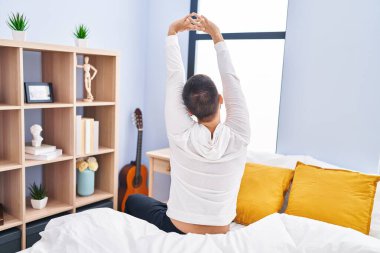 Genç İspanyol adam yatak odasında kollarını gererek uyanıyor.